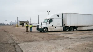 two workers in safety vests standing beside parked semi-truck at commercial lot